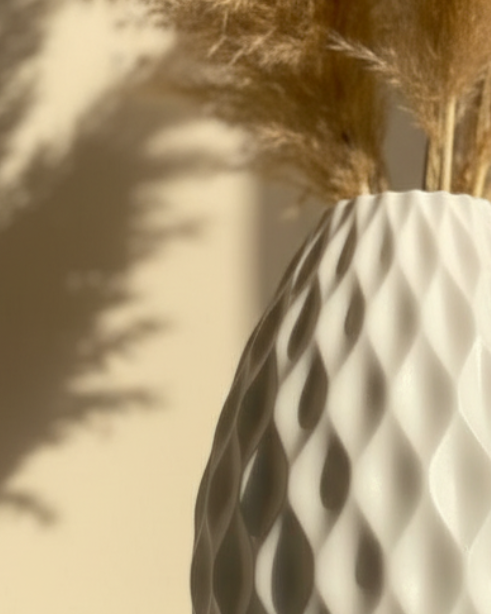 White textured vase with dried pampas grass against a beige wall