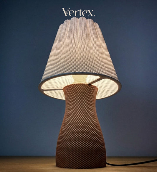 A table lamp with a textured, woven mushroom-shaped base in a warm brown tone and a matching textured white shade, shown lit against a dark blue background. The brand name 'Vertex.