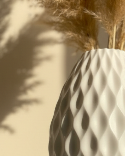 White textured vase with dried pampas grass against a beige wall