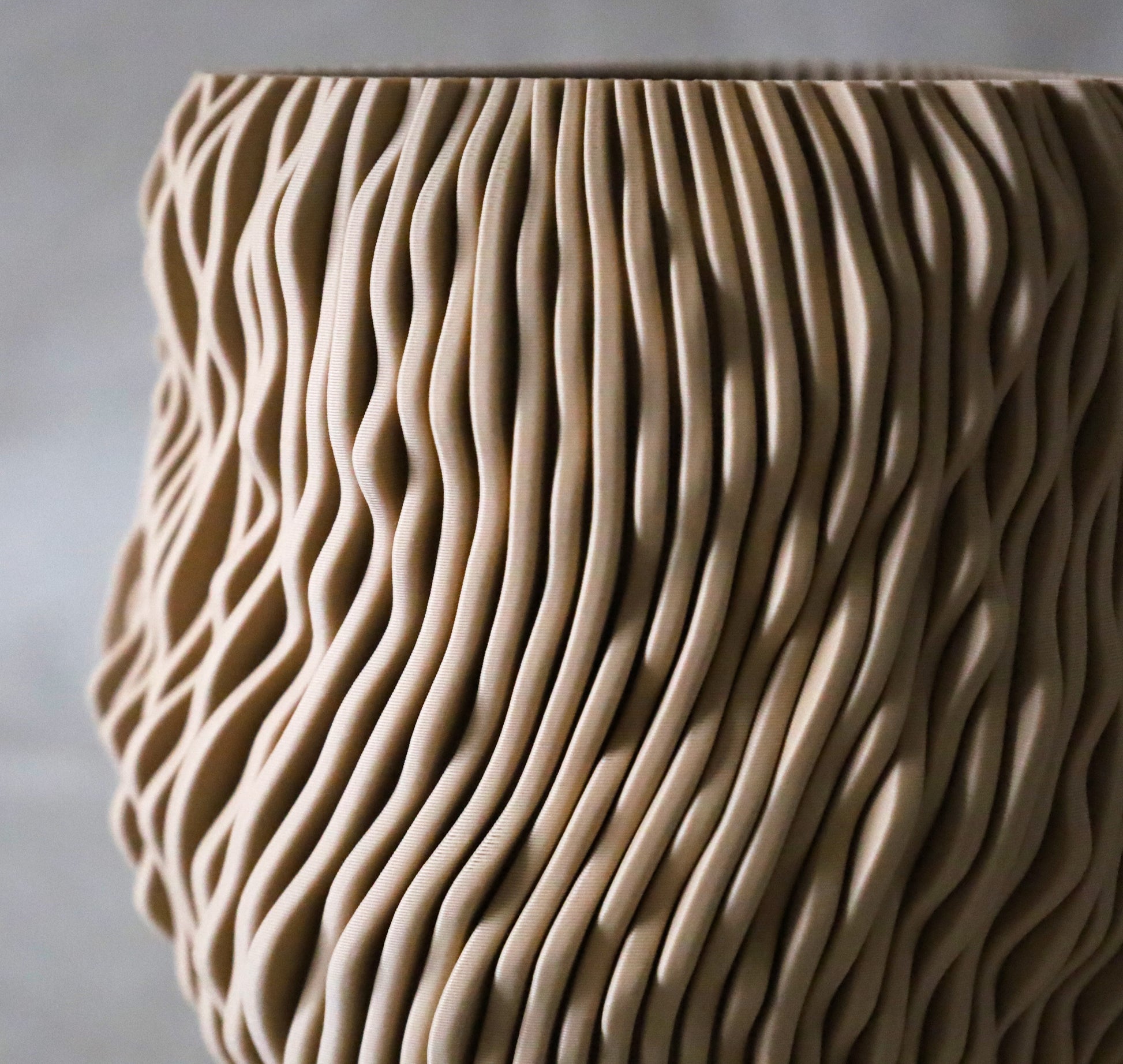 Beige ceramic planter with wavy texture on a gray background