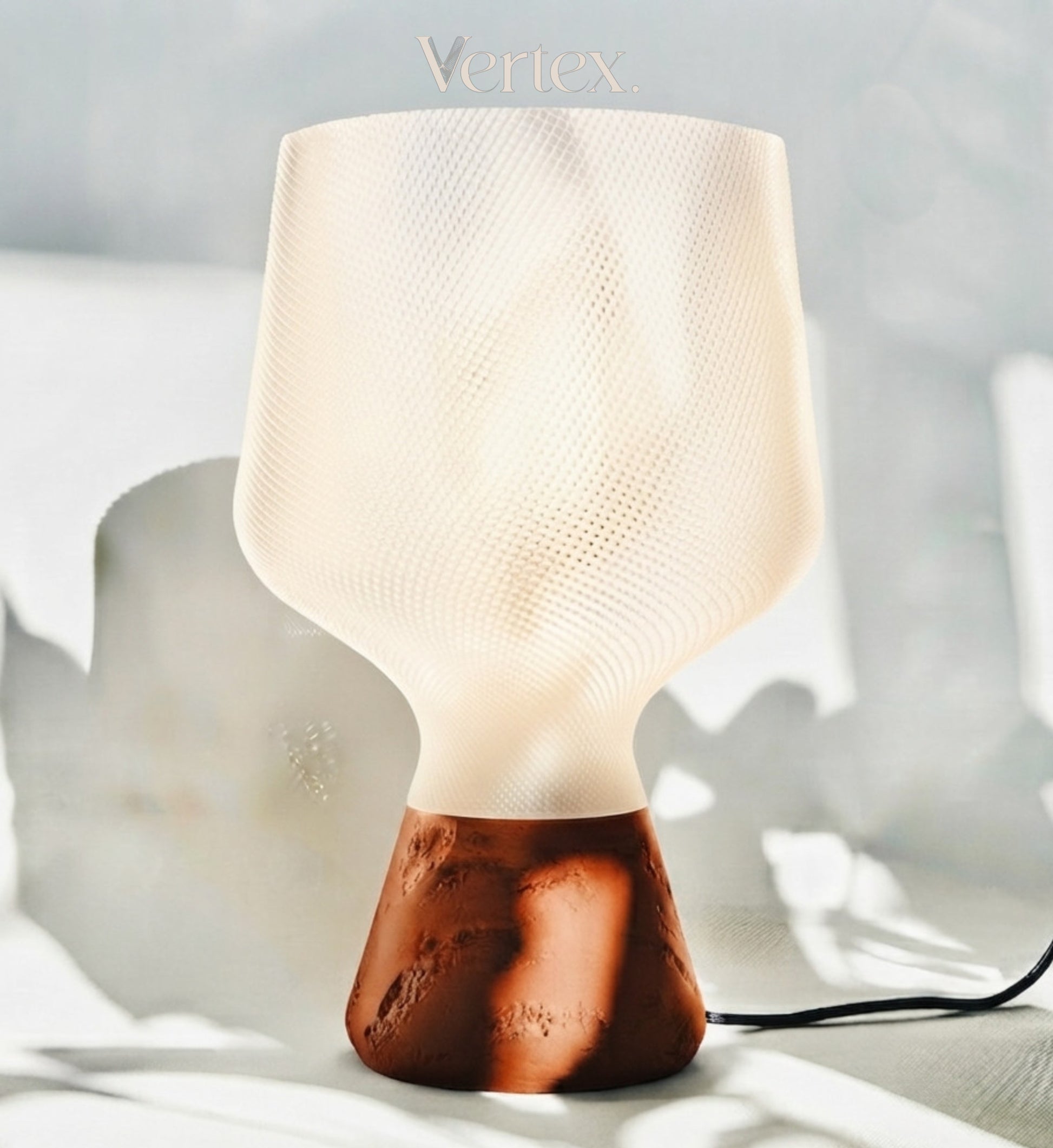 A modern table lamp with a textured, frosted off-white shade and a sculptural terracotta-colored base, shown on a light gray surface with soft shadows. The brand name 'Vertex' is printed above the lamp.