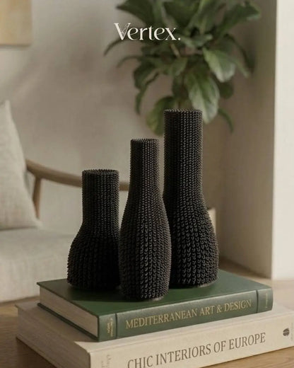 Three black textured vases on books with 'Vertex' branding in the corner.