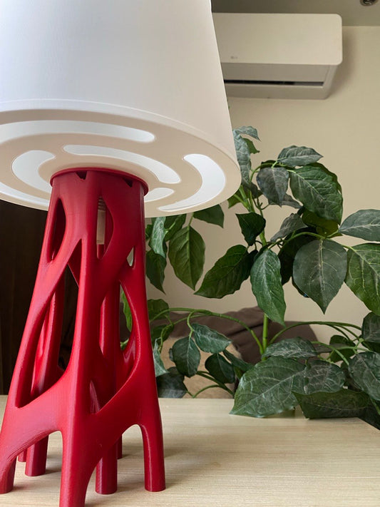 Table lamp with red base and white shade on a wooden stool against a beige wall, featuring the brand 'Vertex'.