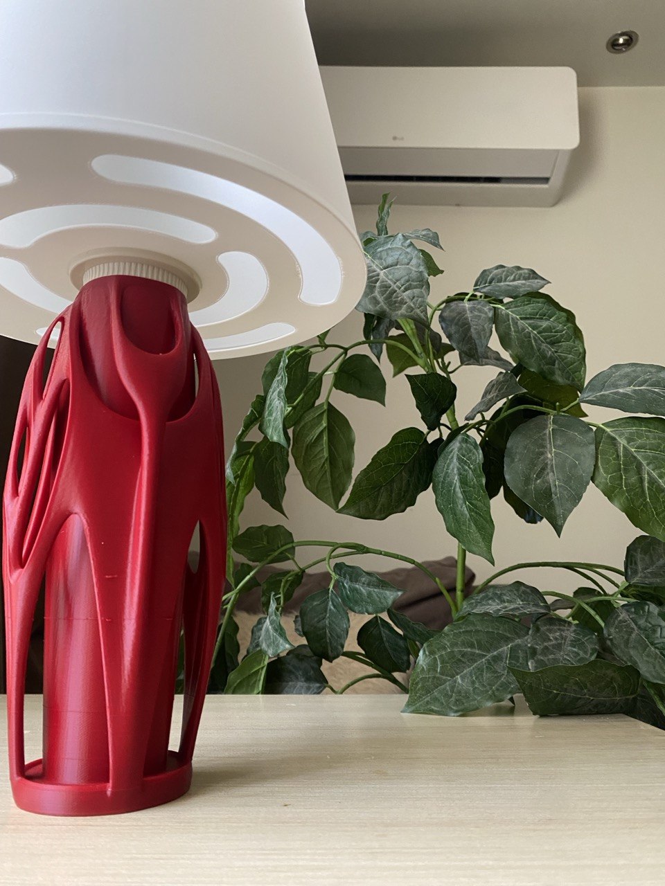 Table lamp with red base and beige shade on a wooden stool against a brown background, featuring the brand 'Vertex'.