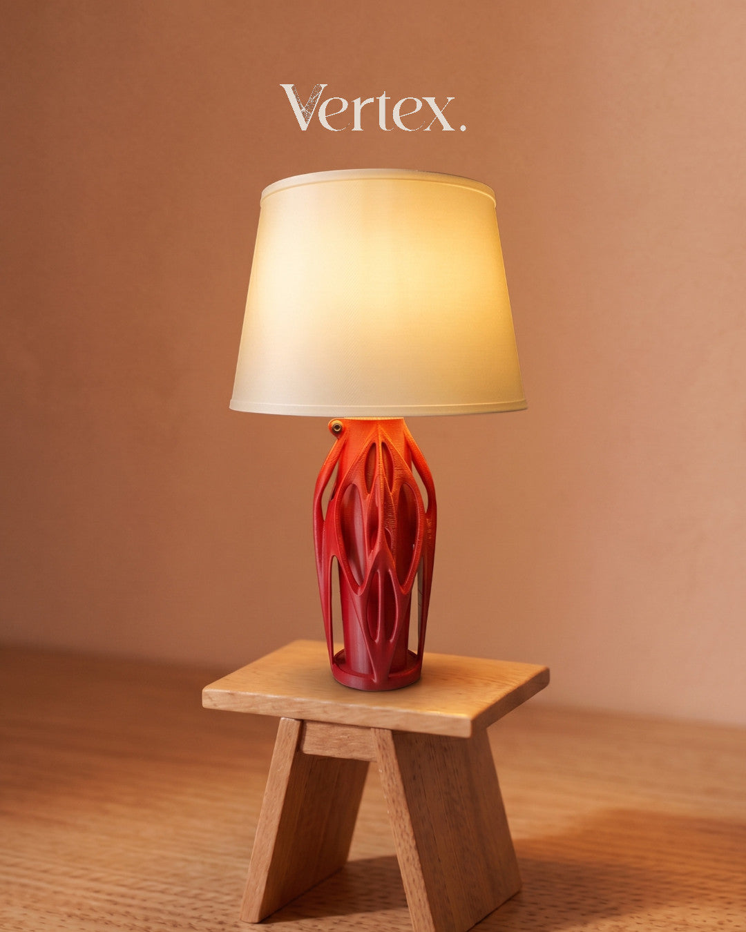 Table lamp with red base and beige shade on a wooden stool against a brown background, featuring the brand 'Vertex'.